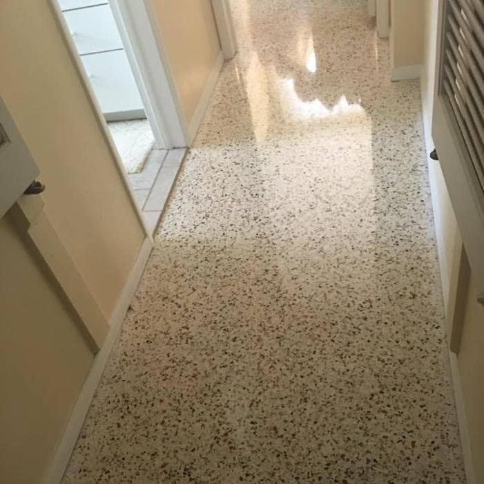 Cleaned terrazzo hallway with tan and brown aggregate and a glossy section at the far end